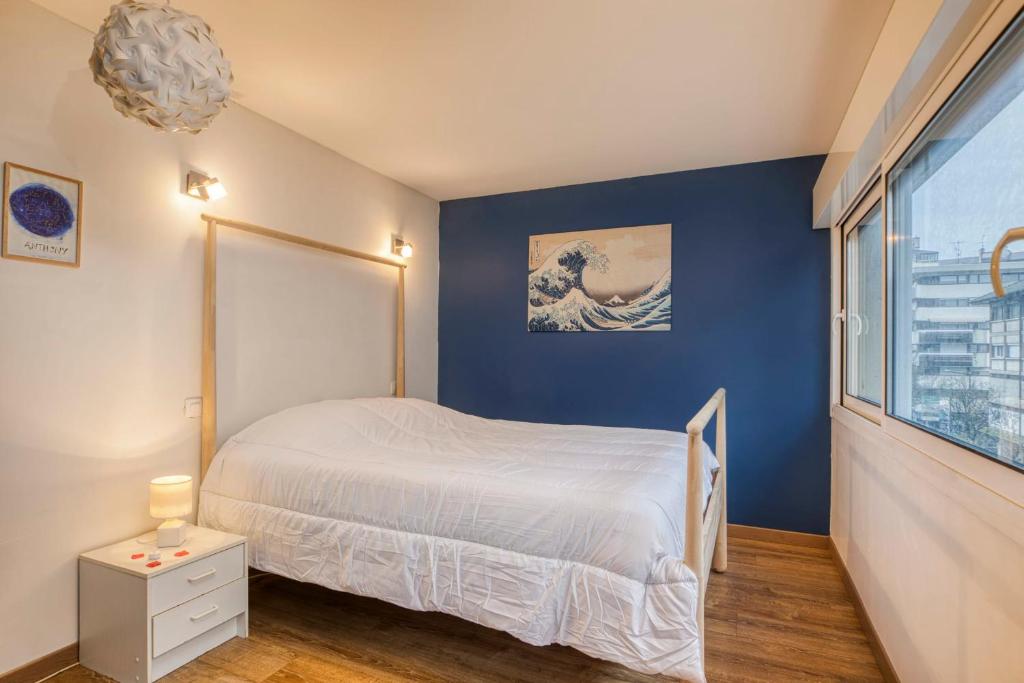 a bedroom with a bed and a blue wall at Spacious and cosy flat in Annecy