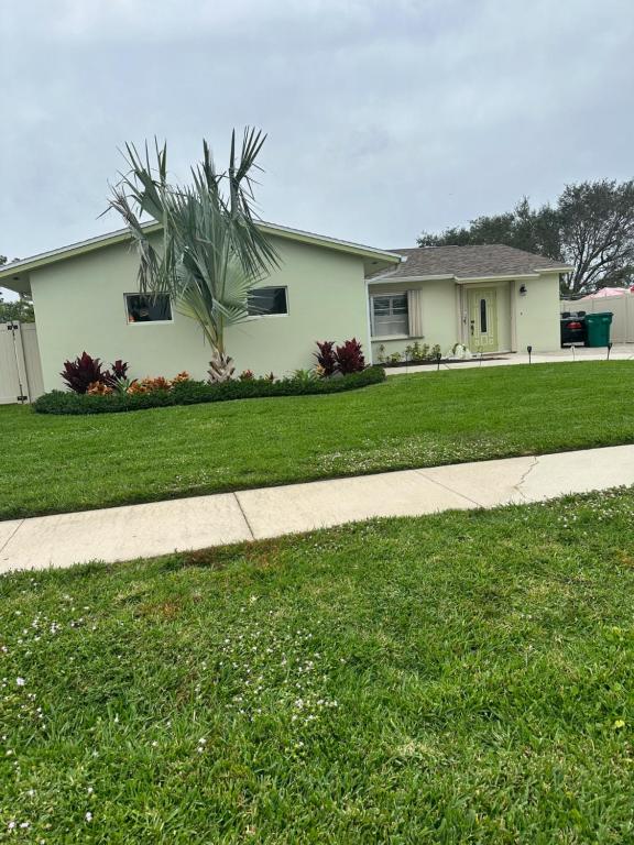 a house with a grass yard and a sidewalk at Freshly Remodeled 1970’s Single Story Villa in Naples