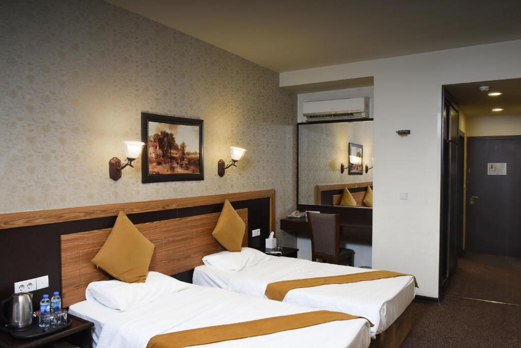 Cette chambre comprend deux lits et un bureau. dans l'établissement Asenappar Hotel, à Erbil
