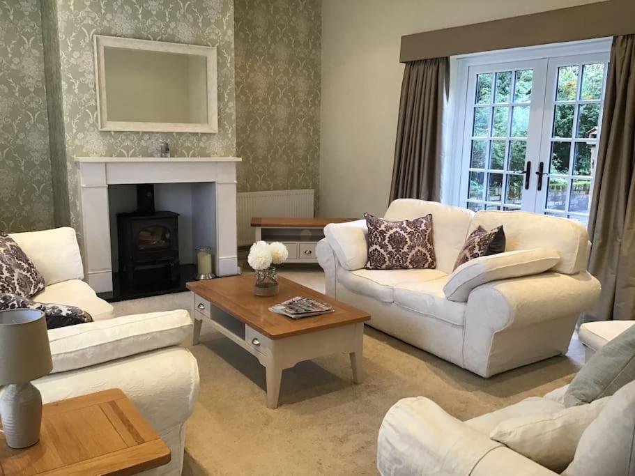 a living room with white furniture and a fireplace at The Coach House at Pitchards in Halstead