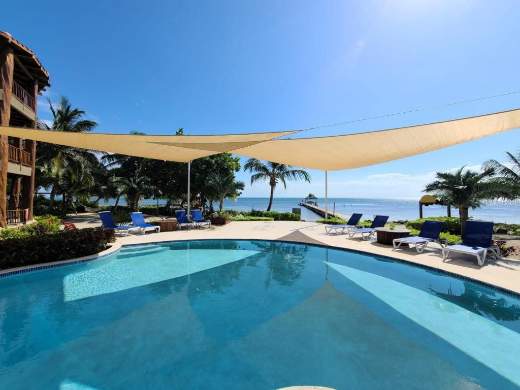 een zwembad met stoelen en een parasol bij Indigo Belize 2B Condo in San Pedro