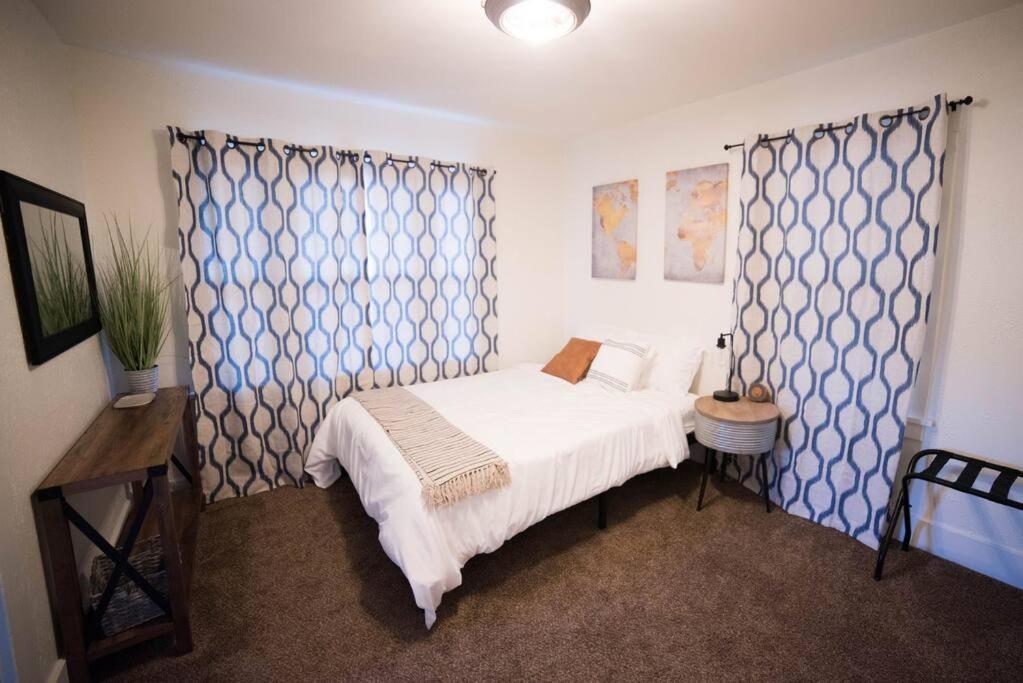 a bedroom with a white bed and blue patterned curtains at Cozy Comfort Minutes From Downtown Klamath Falls in Klamath Falls
