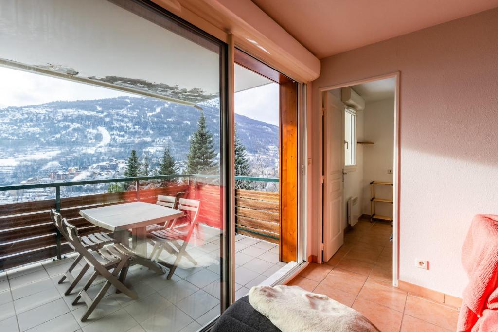 Zimmer mit einem Balkon mit Tisch und Stühlen in der Unterkunft Comfortable nest with mountain views in Briançon