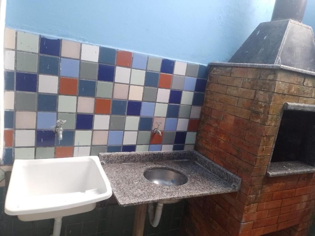 a bathroom with a sink and a tile wall at Reencanto Sonho Azul in Palhoça