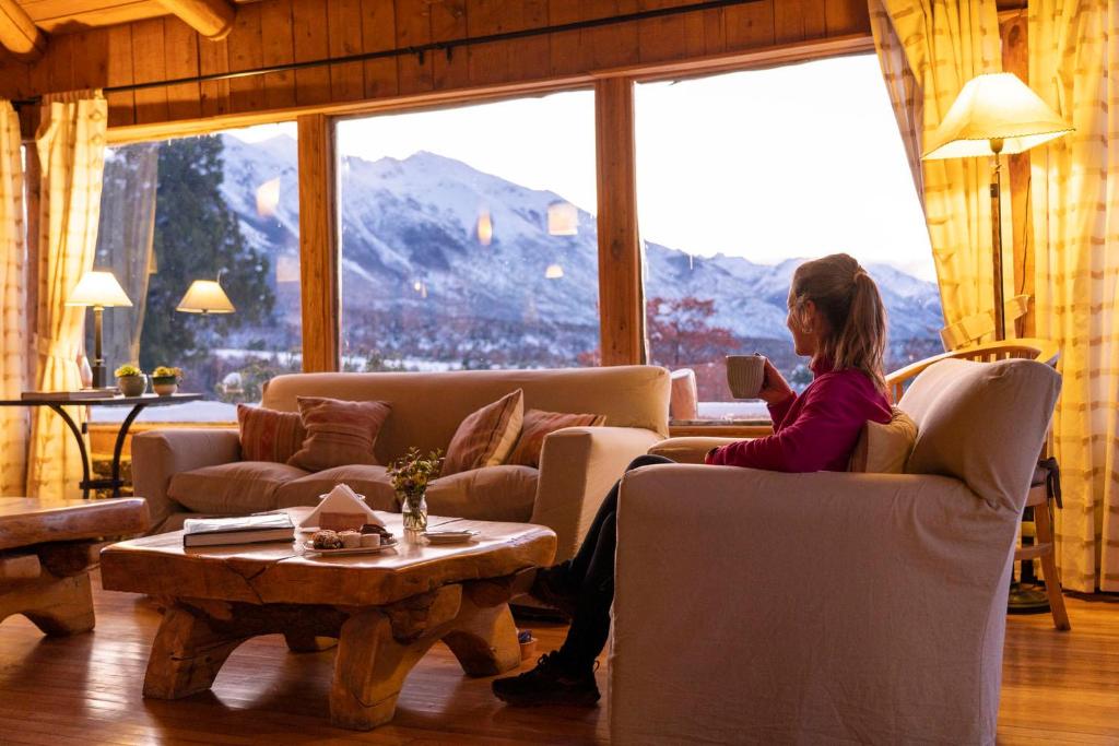 a woman sitting on a couch reading a book at Pueblo Alto Lodge in Parque Nacional Los Alerces