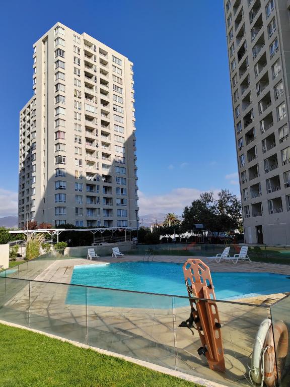 uma piscina com cadeiras e dois edifícios altos em Lindo departamento a pasos de la playa em Coquimbo