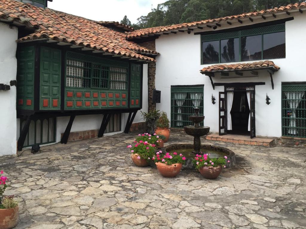 ein Haus mit Topfpflanzen vor einem Brunnen in der Unterkunft Hotel San Luis de Ucuengá in Nobsa