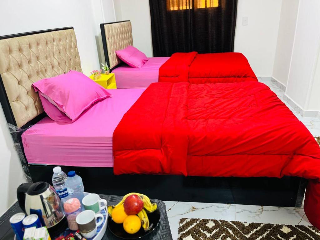 Duas camas com edredões vermelhos e uma taça de fruta. em four pyramids Guest house em Cairo