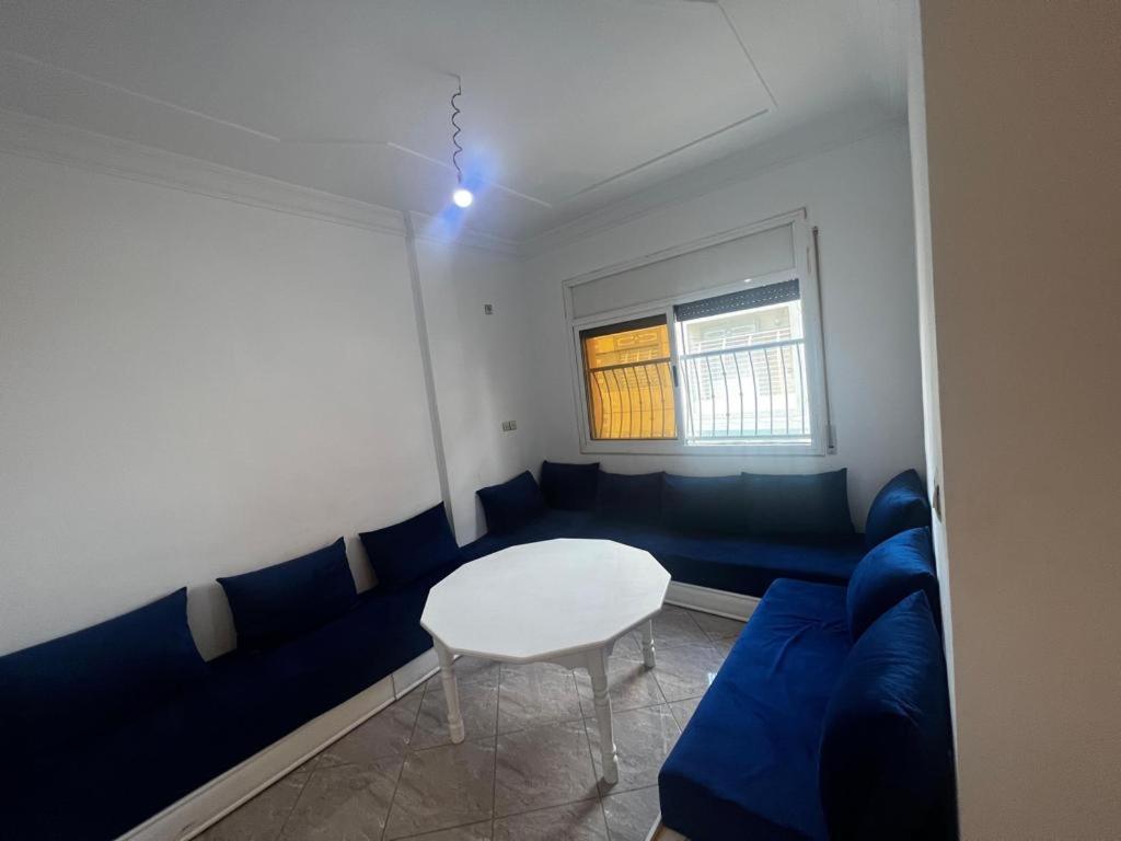 - un salon avec un canapé bleu et une table dans l'établissement Nouvel appartement idéal, à Guercif
