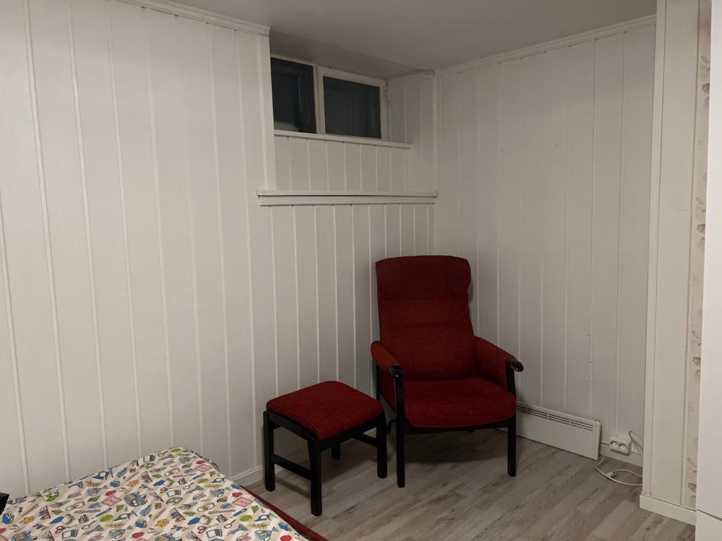 una camera con una sedia, una sedia rossa e un letto di Råstadveien 20 a Sandefjord