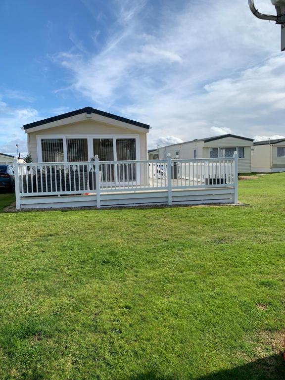 a house with a white fence in a yard at Aurora luxury beach lodge in Lossiemouth