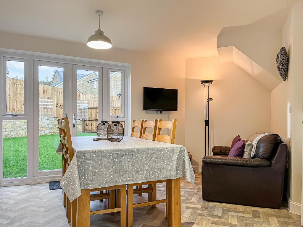 a dining room with a table and a couch at Crawshaw Cottage in Buxton