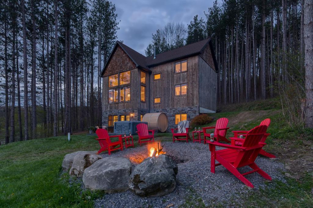 uma fogueira com cadeiras vermelhas em frente a uma casa em New & Stunning Chalet! Reno'd, Hot-Tub, Barrel Sauna, Slope Views, Fire Pit em Ellicottville