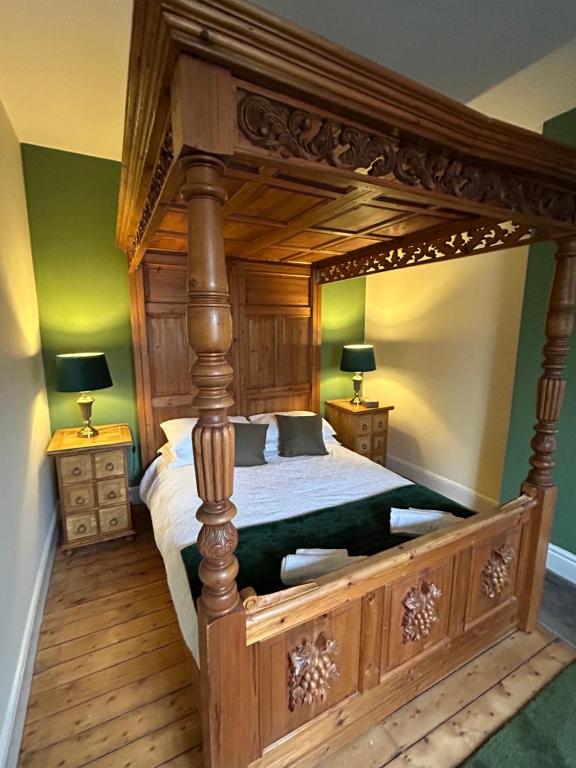 ein großes hölzernes Himmelbett in einem Zimmer mit zwei Lampen in der Unterkunft The Buxton Retreat A Luxurious 3-Storey Townhouse with Four Poster Bed and Double Jacuzzi Bath" in Buxton