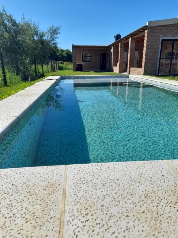 due foto di una piscina davanti a una casa di La casona del Paso a Paso de la Patria