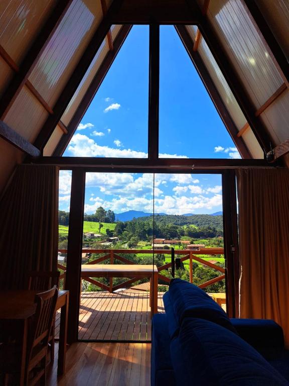 a living room with a large window with a view at Chalés Roma in Santo Antônio do Pinhal