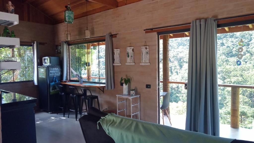 eine Küche und ein Wohnzimmer mit Fenstern und einer Theke in der Unterkunft Sonho na Serra Chalé 2 in Gonçalves
