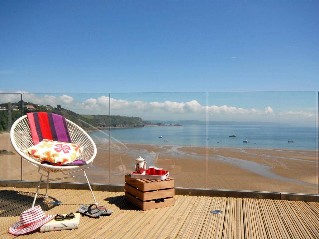 a chair on a balcony with a view of a beach at Ty Mair in Tenby
