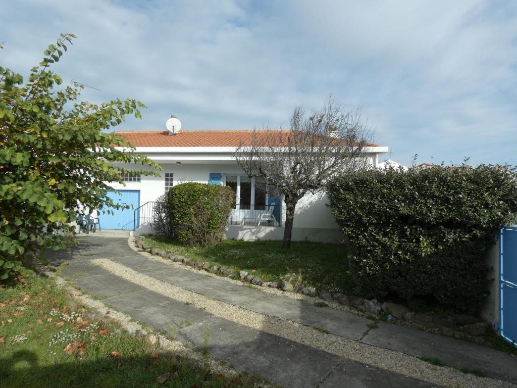 una casa blanca con un árbol y una entrada en Maison Notre-Dame-de-Monts, 3 pièces, 4 personnes - FR-1-540-248, en Notre-Dame-de-Monts