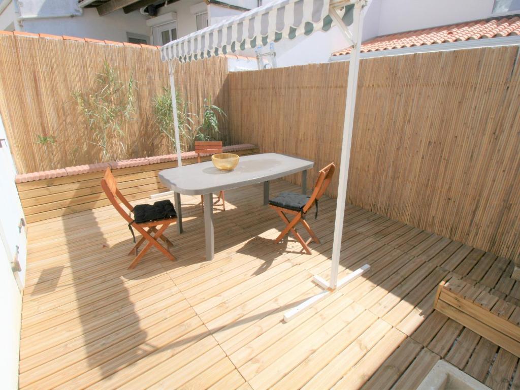 une table et deux chaises sur une terrasse en bois dans l'établissement À 100m de la plage, maison idéale avec terrasse et équipements complets - FR-1-22-321, à La Tranche-sur-Mer
