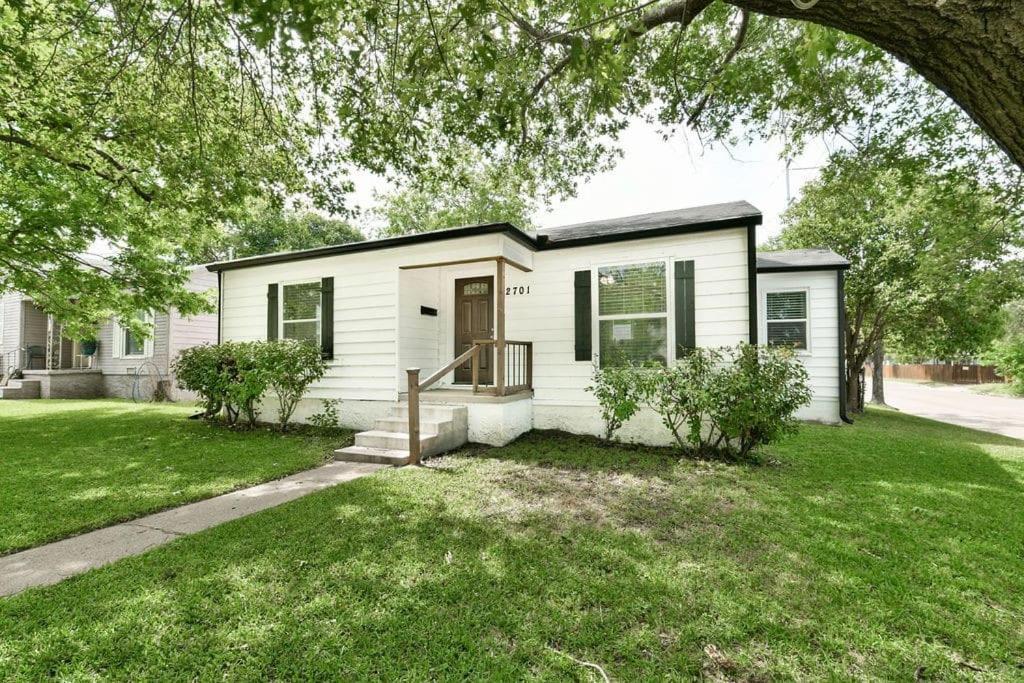 ein kleines weißes Haus mit einem grünen Hof in der Unterkunft Pecan Hill House in Waco