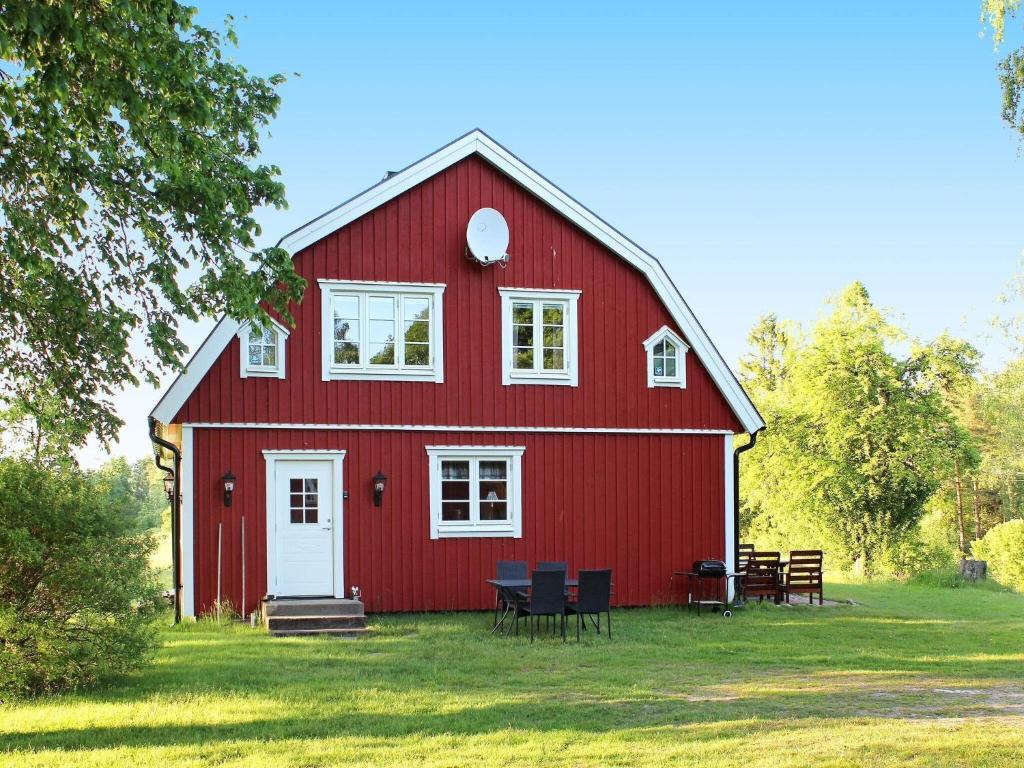 a red barn with tables and chairs in the grass at 7 person holiday home in ÖXABÄCK-By Traum in Öxabäck