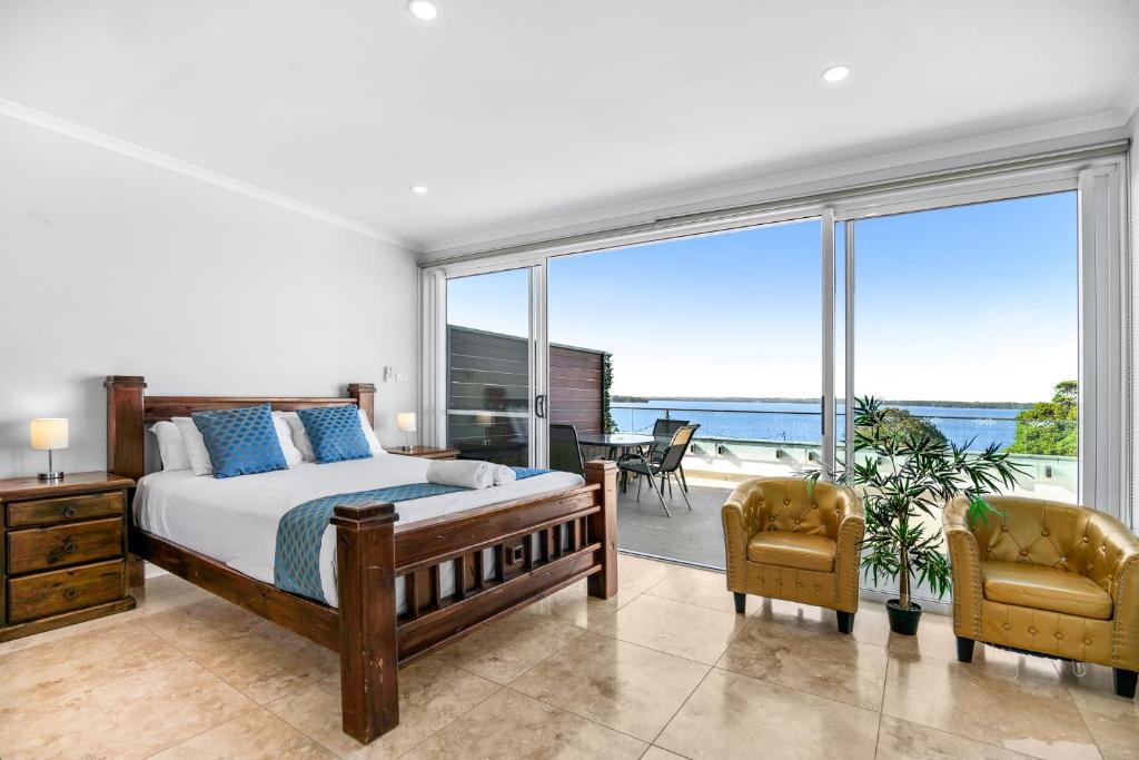 a bedroom with a bed and a view of the ocean at Lakes Resort in Toukley
