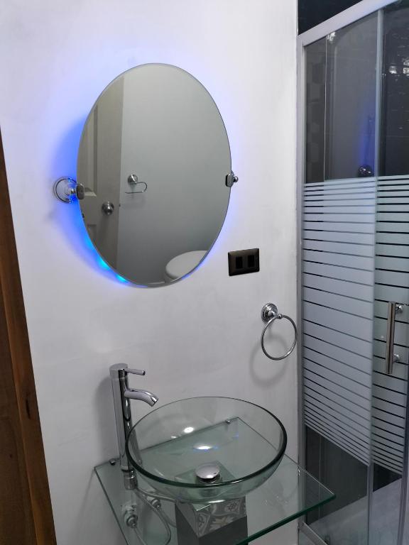 La salle de bains est pourvue d'un lavabo en verre et d'un miroir. dans l'établissement Habitaciones Barrancas, à San Antonio