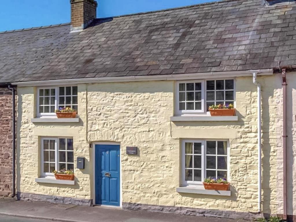 a white stone house with blue doors and windows at Coachingmans Cottage in Trecastle