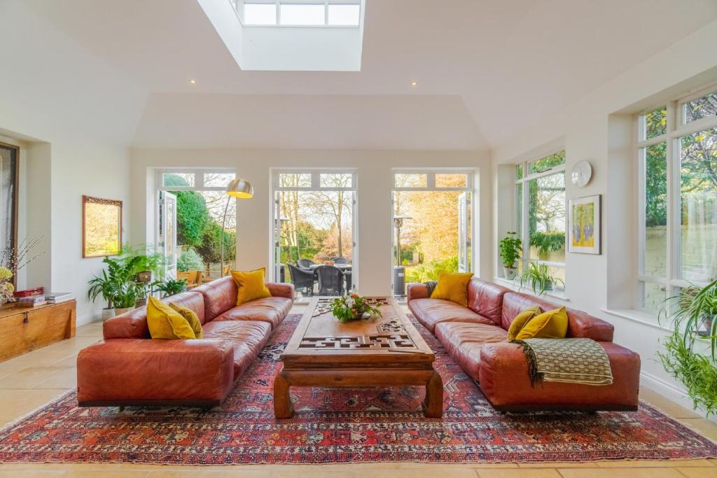 een woonkamer met 2 leren banken en een salontafel bij Stunning 6-bedroom countryside home in Reading