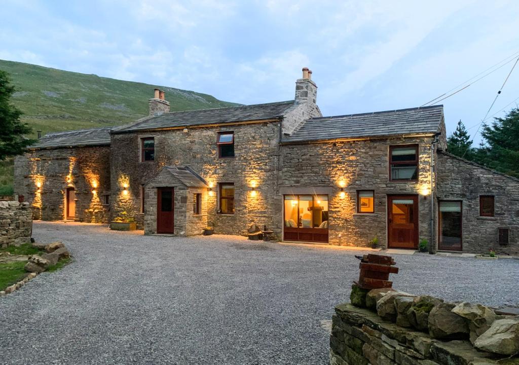 une ancienne maison en pierre avec des lumières dans une allée. dans l'établissement Red Squirrel Cottage, à Hawes