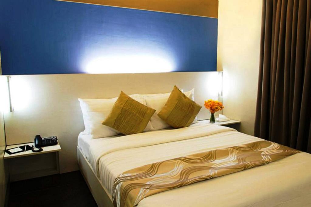 a bedroom with a large bed with a blue headboard at Pillows Hotel Cebu in Cebu City