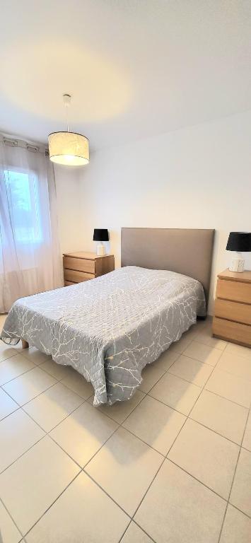 une chambre avec un lit avec une couette blanche dans l'établissement Logement thermale et de tourisme Les Acacias 4, à Jonzac