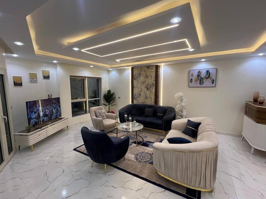 uma sala de estar com um sofá e cadeiras e uma televisão em LAYAN LUXURY APARTMENT no Cairo