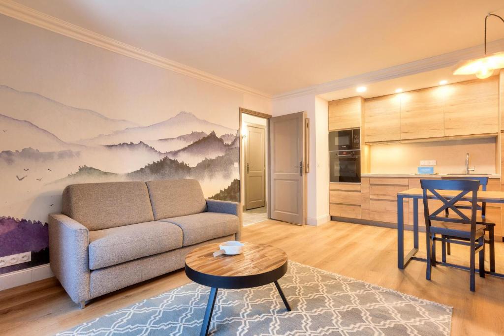uma sala de estar com um sofá, uma mesa e uma cozinha em Résidence Les Arcs Le Village - maeva Home - Appartement pièces - Exclusiv 761 em Arc 1950