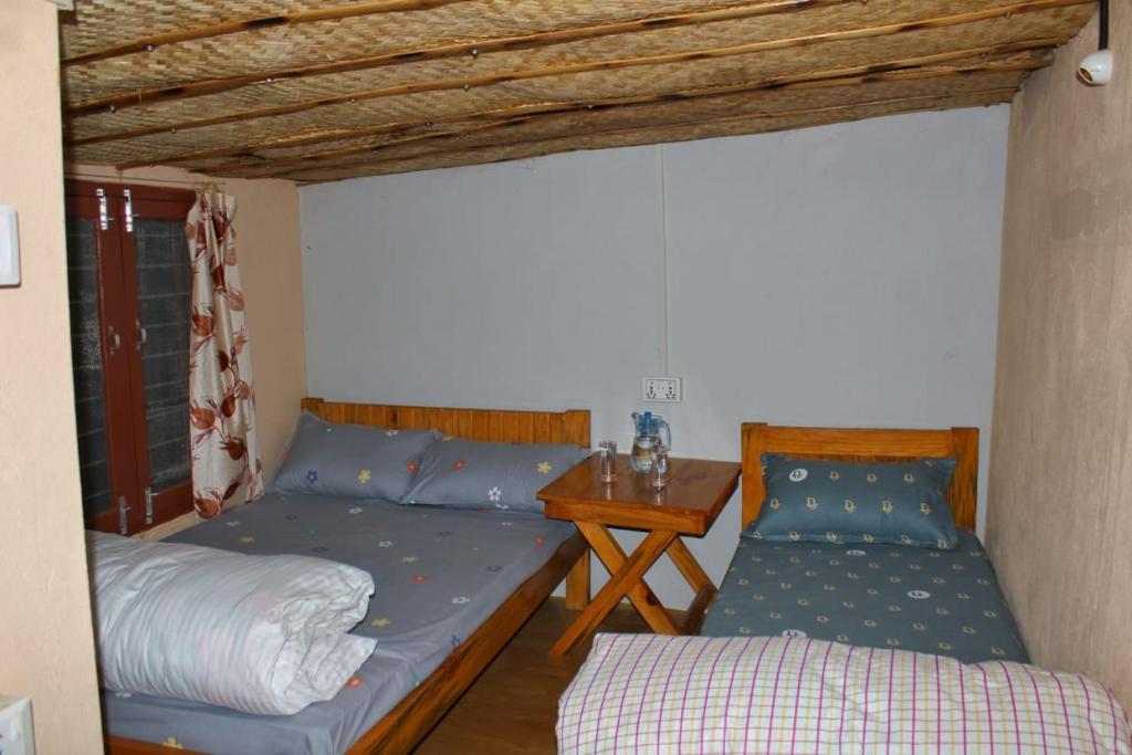 a bedroom with two beds and a table with a desk at Panchas Retreat Homestay in Kāskī