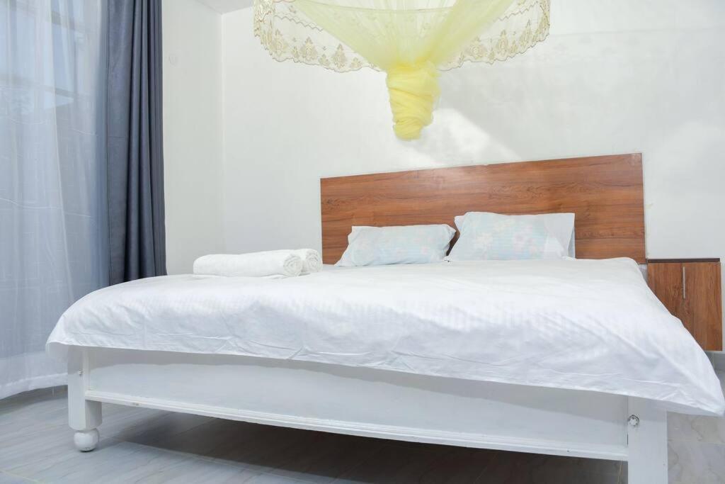 - un lit blanc avec une tête de lit en bois dans une chambre dans l'établissement Tulivu homes, 