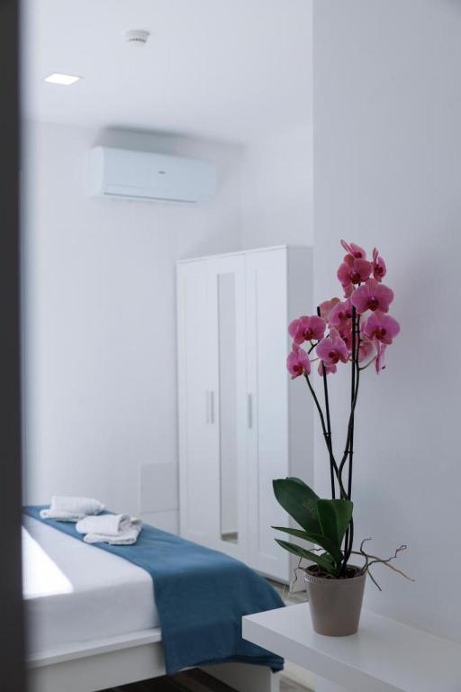 a vase with pink flowers on a table in a bedroom at Essentia Rooms & Relax in Vasto