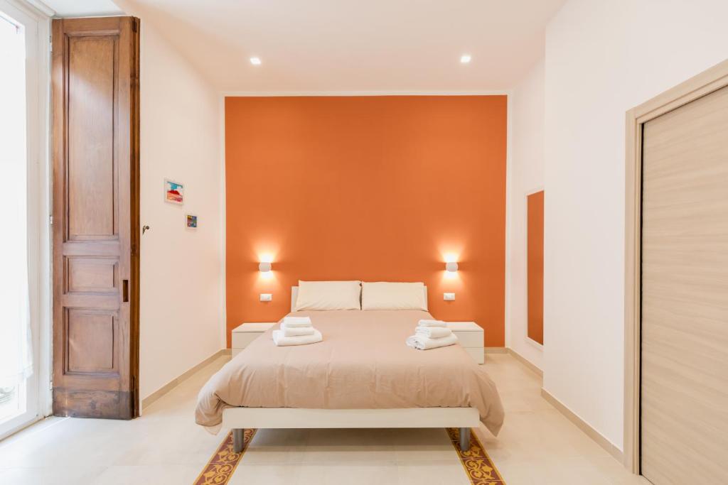een slaapkamer met een bed en een oranje muur bij O' Munasterio e Santa Chiara in Napels