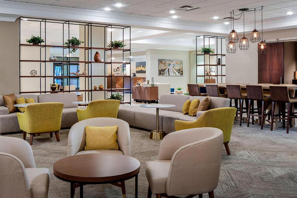 a waiting room with couches and tables and chairs at Sheraton Suites Market Center Dallas in Dallas