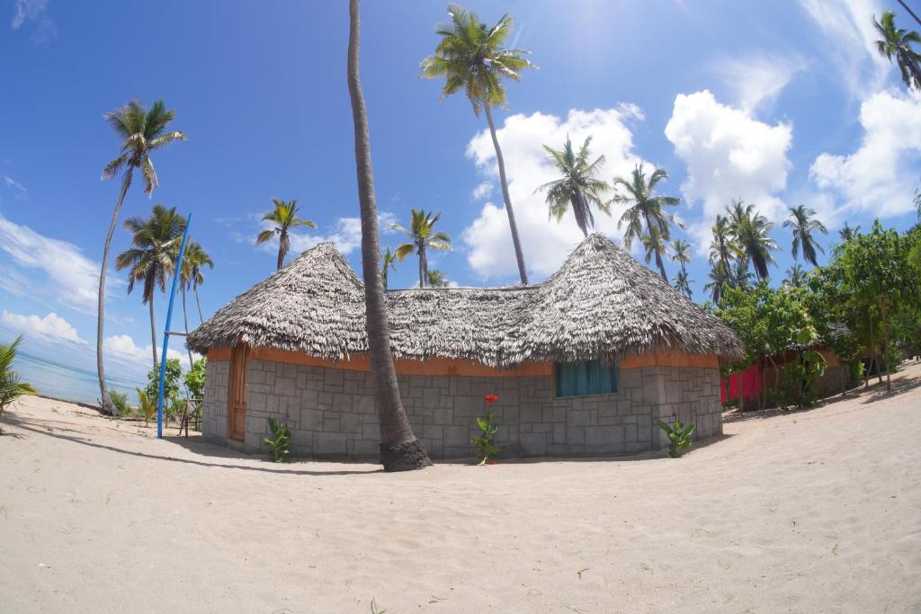 een klein gebouw aan het strand met palmbomen bij AFLII Beach Club ( Zanzibar Beach ) in Mtwara