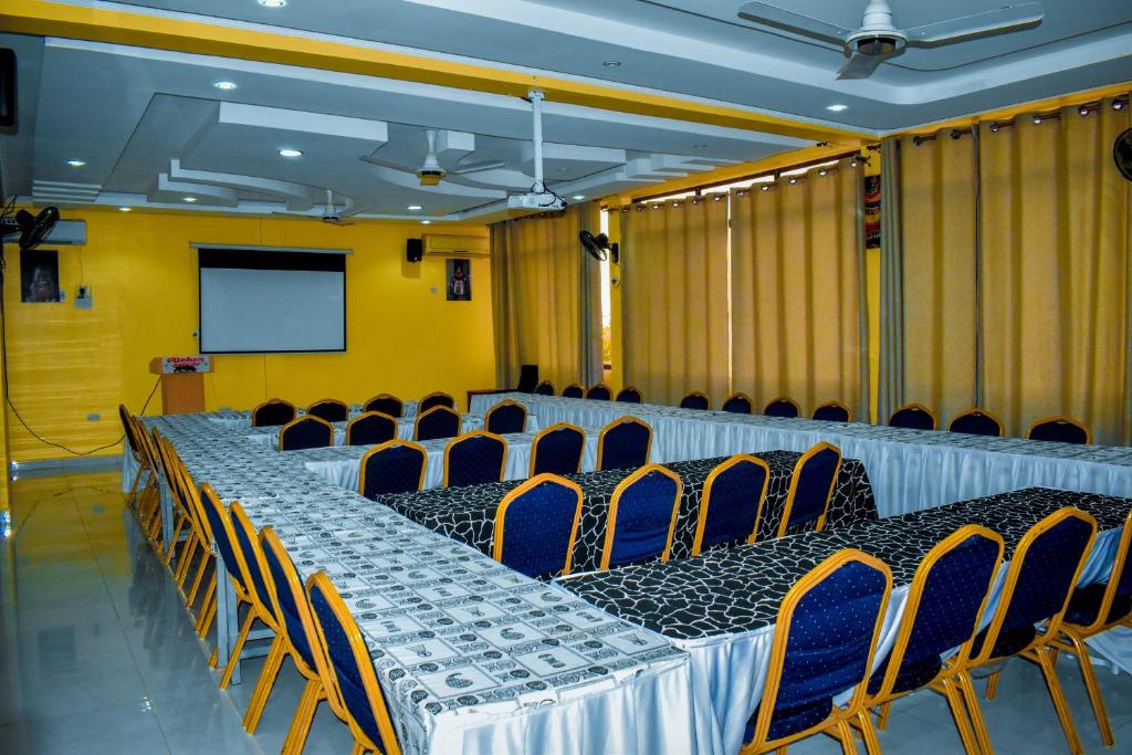 a conference room with tables and chairs and a screen at Ateker Hotel in Lodwar