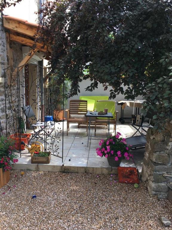 a patio with a bench and a table and flowers at Appartement, Terrasse et jardin in Craponne