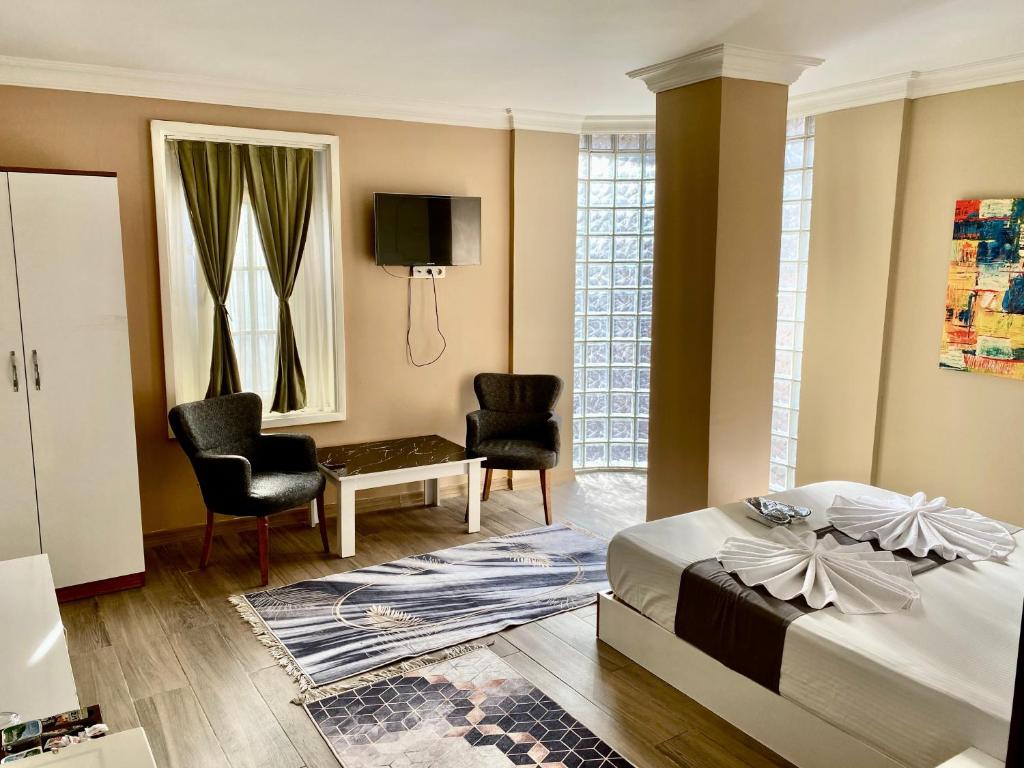 a bedroom with a bed and two chairs and a tv at Airport Best Hotel in Istanbul