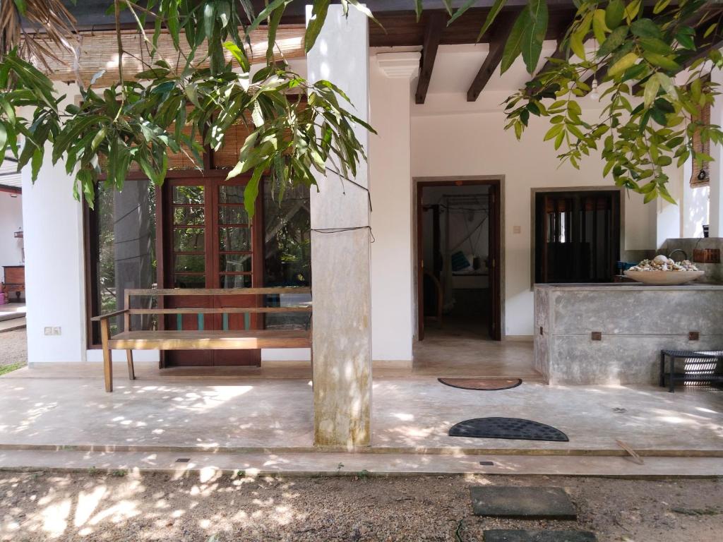 a porch of a house with a bench and a tree at Silva Rest in Unawatuna
