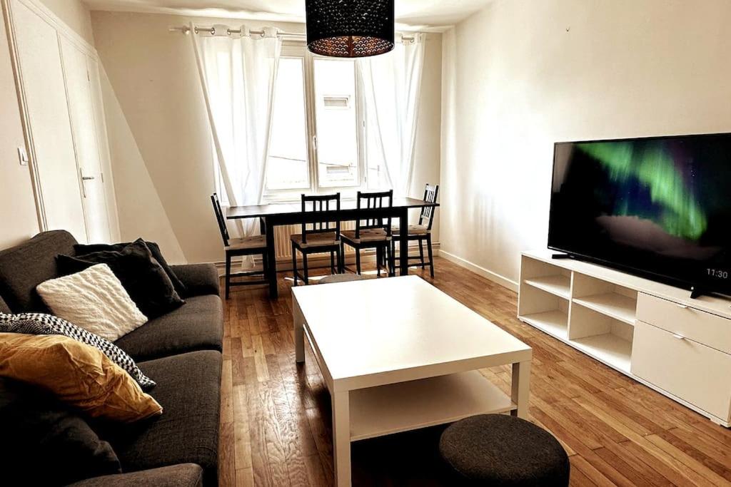 a living room with a couch and a tv and a table at Appartement 6 places, 3 chambres in La Mulatière