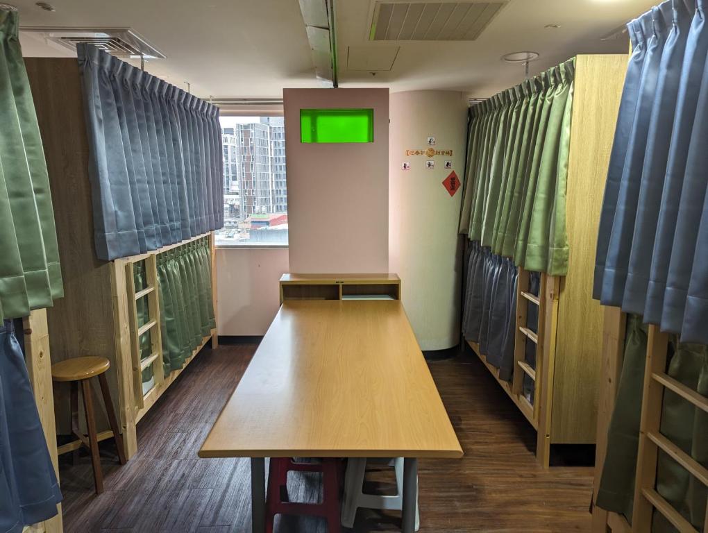 a room with a table and a room with windows at Hey Bear Capsule Hotel in Taipei