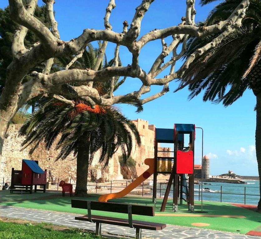 a playground with a slide in a park next to a tree at 4VSE-LAM55 Appartement avec vue dégagée Collioure proche plage in Collioure