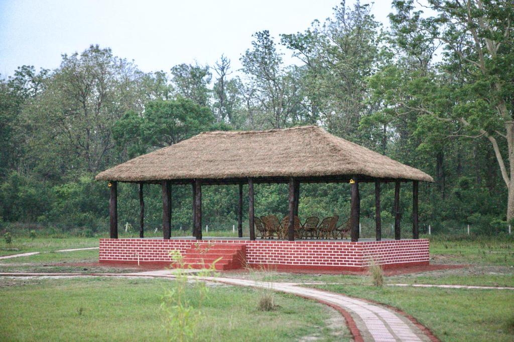 a gazebo with a straw roof in a field at Camp TigerLily - Dudhwa in Bhīra