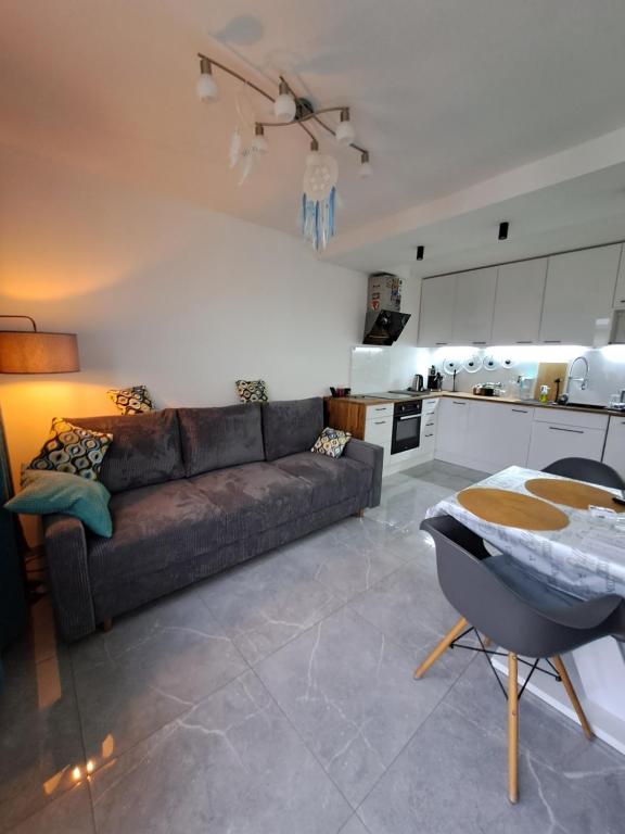 a living room with a couch and a kitchen at Apartament Morze i Las in Mrzeżyno